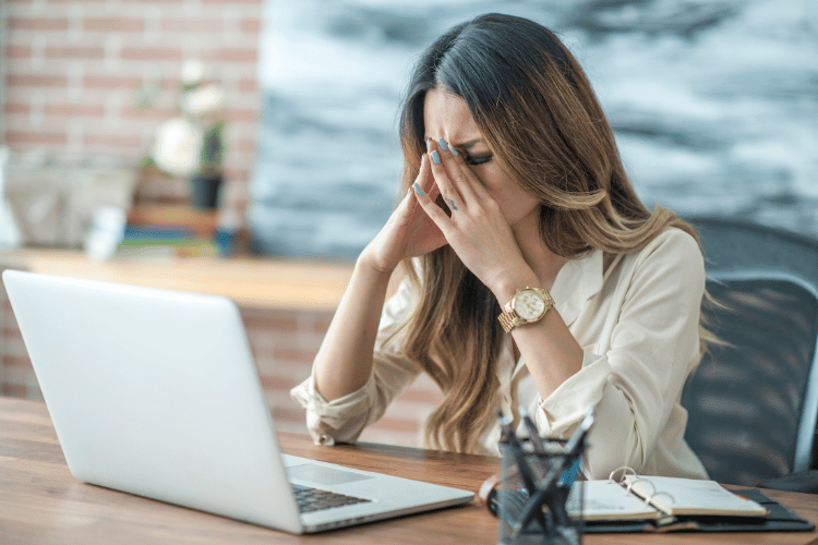 A young woman felling stressed at her office putting her hand on her face