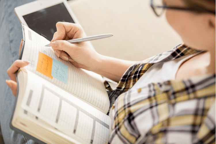 Close-up of a woman writing down in her notebook