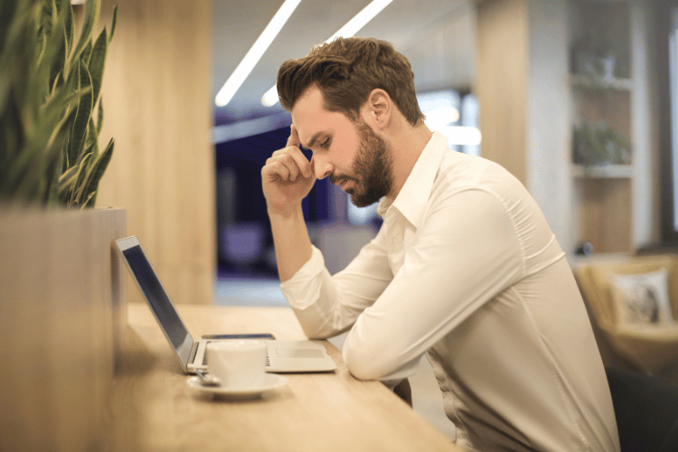 Man with Hand Thinking and Looking at Laptop